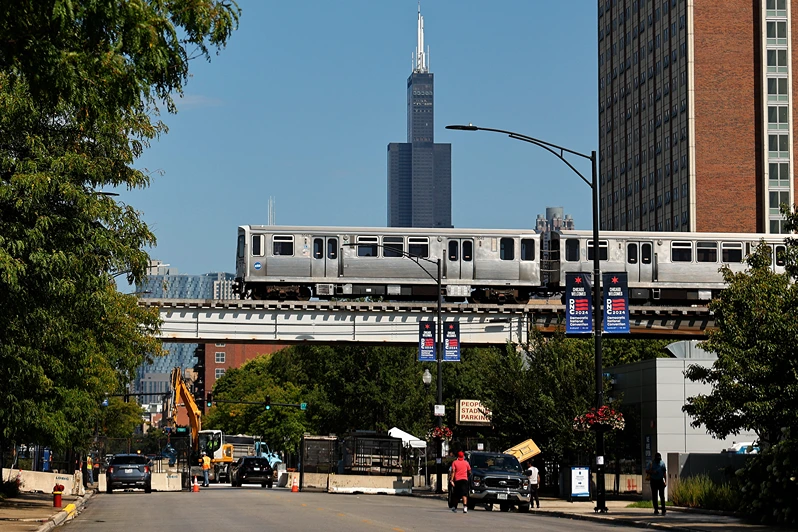 CHICAGO, ILLINOIS - AUGUST 17: A Chicago Transit Authority Pink Line elevated train rolls over the 10-foot-tall security perimeter fence around the the United Center ahead of the next week's Democratic National Convention on August 17, 2024 in Chicago, Illinois. The convention will be held in Chicago on August 19-22. (Photo by Chip Somodevilla/Getty Images)