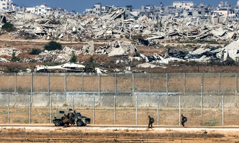 Israeli army soldiers walk towards an armoured vehicle at a position along the border fence with the Gaza Strip in southern Israel on September 30, 2025. The US president on September 29 laid out a plan to end the war in Gaza and Israeli Prime Minister Benjamin Netanyahu said he backed the proposal. The two allies demanded approval by Hamas, whose October 7, 2023 attack triggered a massive Israeli offensive, with Netanyahu warning he will "finish the job" if Hamas says no. (Photo by Jack GUEZ / AFP) (Photo by JACK GUEZ/AFP via Getty Images)