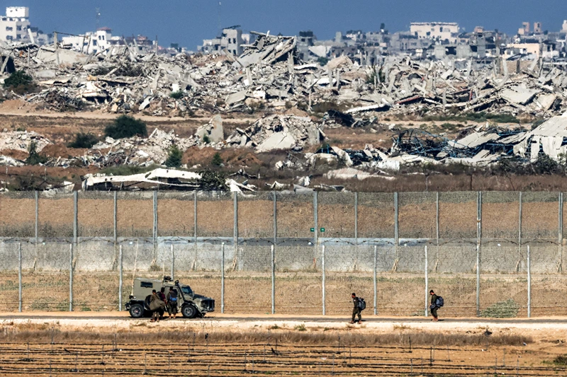 Israeli army soldiers walk towards an armoured vehicle at a position along the border fence with the Gaza Strip in southern Israel on September 30, 2025. The US president on September 29 laid out a plan to end the war in Gaza and Israeli Prime Minister Benjamin Netanyahu said he backed the proposal. The two allies demanded approval by Hamas, whose October 7, 2023 attack triggered a massive Israeli offensive, with Netanyahu warning he will "finish the job" if Hamas says no. (Photo by Jack GUEZ / AFP) (Photo by JACK GUEZ/AFP via Getty Images)