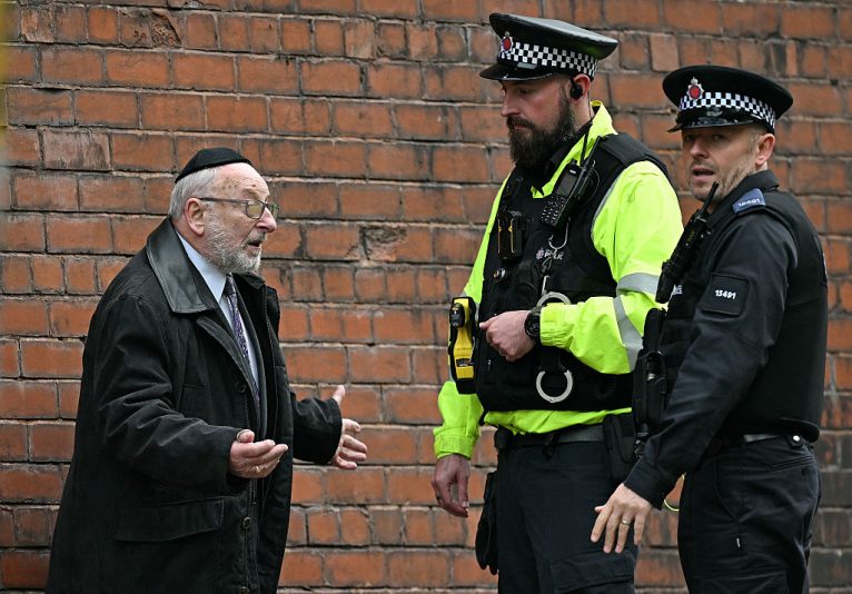 Police officers talk with a member of the local community near Heaton Park Hebrew Congregation synagogue in Crumpsall, north Manchester, on October 2, 2025, following an attack at the synagogue. Two people were killed and three wounded in a car ramming and stabbing incident outside a synagogue in Manchester, northwest England, on Thursday, police said. "A man believed to be the offender was shot by GMP (Greater Manchester Police) Firearms Officers and is also believed to be deceased," the force said on X, adding his death could not yet be confirmed due to "suspicious items on his person". (Photo by Oli SCARFF / AFP) (Photo by OLI SCARFF/AFP via Getty Images)