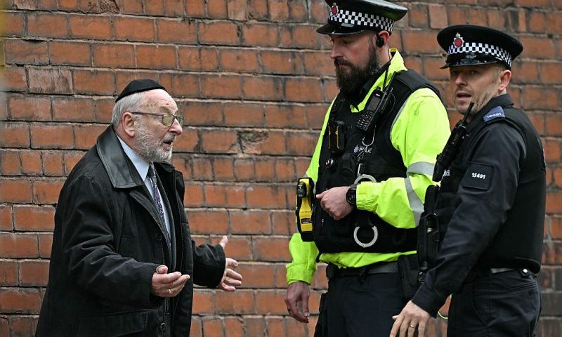 Police officers talk with a member of the local community near Heaton Park Hebrew Congregation synagogue in Crumpsall, north Manchester, on October 2, 2025, following an attack at the synagogue. Two people were killed and three wounded in a car ramming and stabbing incident outside a synagogue in Manchester, northwest England, on Thursday, police said. "A man believed to be the offender was shot by GMP (Greater Manchester Police) Firearms Officers and is also believed to be deceased," the force said on X, adding his death could not yet be confirmed due to "suspicious items on his person". (Photo by Oli SCARFF / AFP) (Photo by OLI SCARFF/AFP via Getty Images)