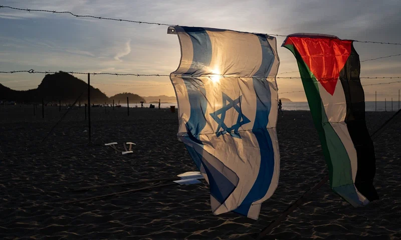 An Israeli and a Palestinian flag hang on an installation set up by members of the Brazilian NGO Rio de Paz at Copacabana beach in Rio de Janeiro, Brazil, on October 4, 2025, featuring photos of Israeli children killed in the bloody October 7, 2023, attack by Hamas on Israel, Palestinian children killed in Israeli bombardments of the Gaza Strip in retaliation, and Brazilian children killed by stray bullets during police operations. The demonstration, featuring 200 photos of Israeli, Palestinian and Brazilian children, denounced the violence that cuts lives short and steals childhoods. (Photo by Pablo PORCIUNCULA / AFP) (Photo by PABLO PORCIUNCULA/AFP via Getty Images)