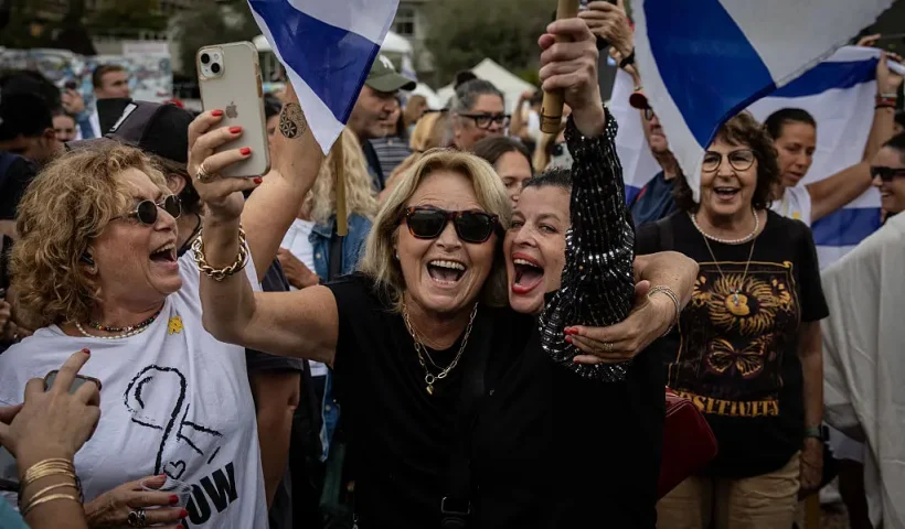 TEL AVIV, ISRAEL - OCTOBER 09: People gather and wave flags in what's known as Hostages Square as they react to the news of the Gaza peace deal on October 09, 2025 in Tel Aviv, Israel. Overnight, the US president announced that Israel and Hamas had agreed to the first phase of a ceasefire plan that would see the release of hostages - held in Gaza after their capture on Oct. 7, 2023 - in the coming days. Israel's government is meeting today to formally approve the deal. (Photo by Chris McGrath/Getty Images)