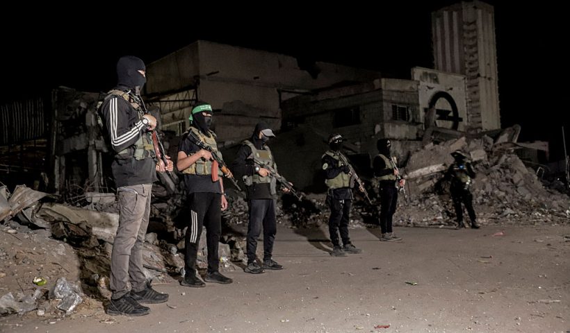 Hamas militants stand guard as vehicles of the International Committee of the Red Cross (not pictured) carry the bodies of hostages held in Gaza since the deadly October 7, 2023, attack, after their transfer by Hamas under a ceasefire and hostage-prisoner exchange agreement between Hamas and Israel, in Gaza City, Gaza Strip, on October 15, 2025. (Photo by Abood Abusalama / Middle East Images via AFP) (Photo by ABOOD ABUSALAMA/Middle East Images/AFP via Getty Images)