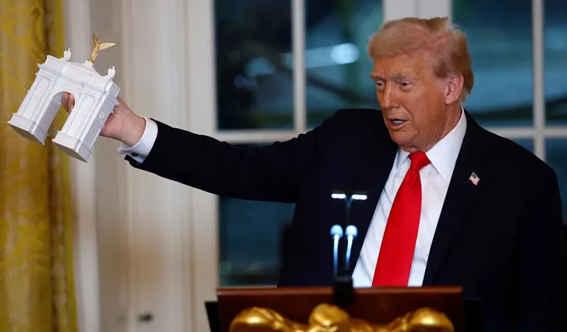 WASHINGTON, DC - OCTOBER 15: U.S. President Donald Trump holds a model of an arch as he delivers remarks during a ballroom fundraising dinner in the East Room of the White House on October 15, 2025 in Washington, DC. Trump hosted organizations and individuals for a fundraising dinner for the new $250 million ballroom addition currently under construction at the White House. (Photo by Kevin Dietsch/Getty Images)