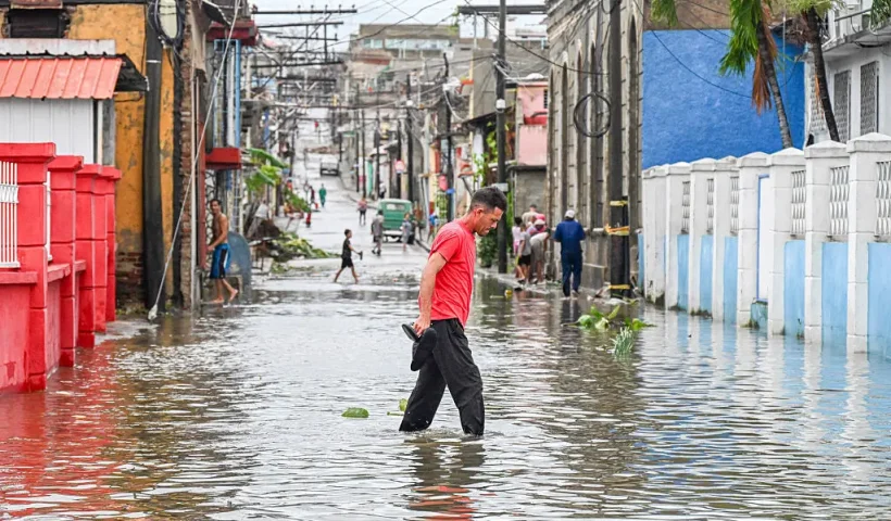 A man walks through a flooded street in a neighborhood affected by Hurricane Melissa in Santiago de Cuba on October 29, 2025. A powerful Hurricane Melissa made landfall in eastern Cuba on Wednesday, causing damage and flooding to homes and streets in Santiago de Cuba province, an AFP team on the ground reported. (Photo by YAMIL LAGE / AFP) (Photo by YAMIL LAGE/AFP via Getty Images)