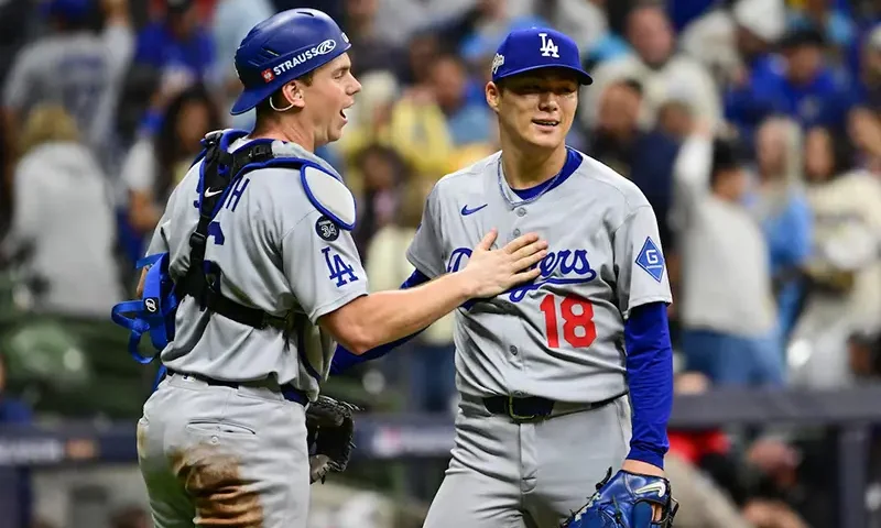 Los Angeles Dodgers catcher Will Smith (16) and pitcher Yoshinobu Yamamoto (18) celebrate after defeating the Milwaukee Brewers in game two of the NLCS round for the 2025 MLB playoffs at American Family Field. Mandatory Credit: Benny Sieu-Imagn Images