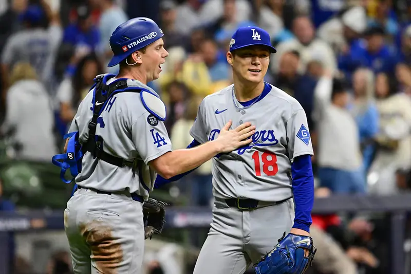 Los Angeles Dodgers catcher Will Smith (16) and pitcher Yoshinobu Yamamoto (18) celebrate after defeating the Milwaukee Brewers in game two of the NLCS round for the 2025 MLB playoffs at American Family Field. Mandatory Credit: Benny Sieu-Imagn Images