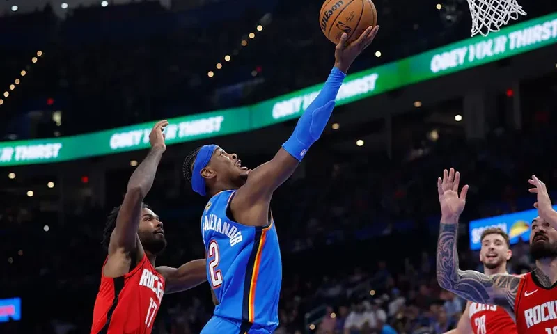 Oklahoma City Thunder guard Shai Gilgeous-Alexander (2) goes up for a basket between Houston Rockets forward Tari Eason (17) and center Steven Adams (12) during the first half at Paycom Center. Mandatory Credit: Alonzo Adams-Imagn Images