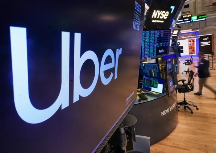 The logo for Uber is displayed above a trading post on the floor of the New York Stock Exchange, Monday, Oct. 20, 2025. (AP Photo/Richard Drew)