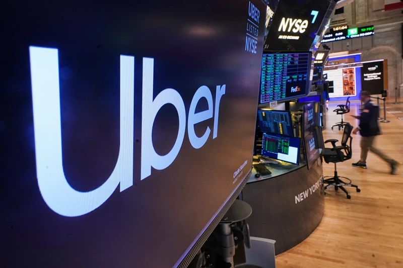 The logo for Uber is displayed above a trading post on the floor of the New York Stock Exchange, Monday, Oct. 20, 2025. (AP Photo/Richard Drew)