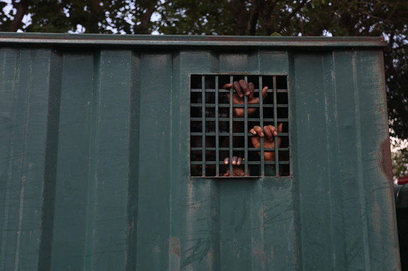 TOPSHOT - The hands of recaptured inmates are seen inside a prison vehicle in Abuja, Nigeria on July 6, 2022, after suspected Boko Haram gunmen attacked the Kuje Medium Prison. Suspected Boko Haram gunmen used explosives to blast their way into a Nigerian prison near the capital, freeing hundreds of inmates in a raid to break out jailed jihadists, the government said on Monday. The brazen attack on the outskirts of Abuja came hours after an ambush on a presidential security convoy in the northwest, in a fresh illustration of Nigeria's security crisis. (Photo by Kola Sulaimon / AFP) (Photo by KOLA SULAIMON/AFP via Getty Images)