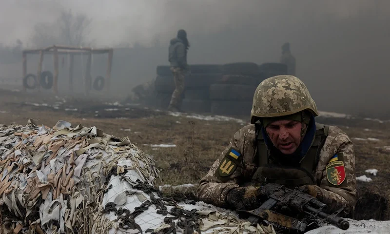 A Ukrainian serviceman of the 24th Mechanized Brigade takes position by sandbags covered with camouflage netting as smoke billows nearby, during training drill at an undisclosed location in the eastern region of Ukraine on March 4, 2025, amid the Russian invasion of Ukraine. (Photo by Tetiana DZHAFAROVA / AFP) (Photo by TETIANA DZHAFAROVA/AFP via Getty Images)