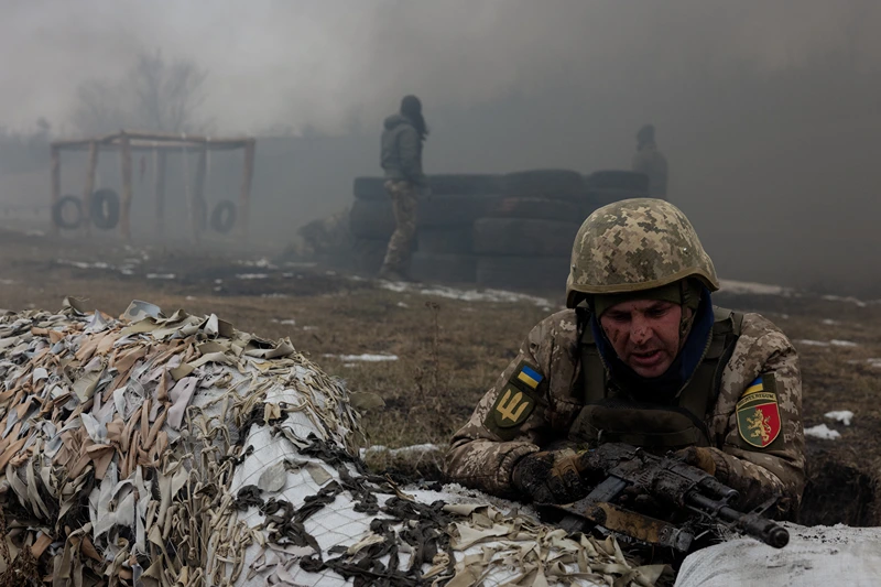 A Ukrainian serviceman of the 24th Mechanized Brigade takes position by sandbags covered with camouflage netting as smoke billows nearby, during training drill at an undisclosed location in the eastern region of Ukraine on March 4, 2025, amid the Russian invasion of Ukraine. (Photo by Tetiana DZHAFAROVA / AFP) (Photo by TETIANA DZHAFAROVA/AFP via Getty Images)
