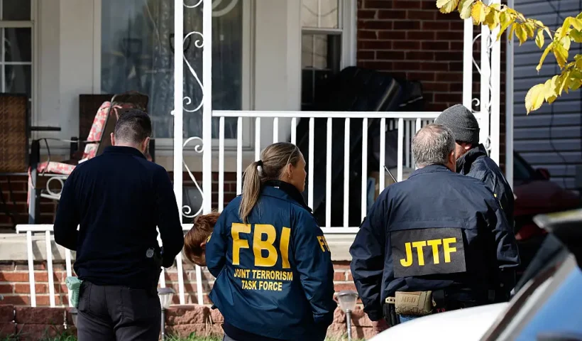 Members of the FBI Joint Terrorism Task Force stand in the front yard as they search a home in Dearborn, Michigan, on October 31, 2025. FBI Director Kash Patel said Friday that the agency had thwarted a "potential terrorist attack" planned in the northern state of Michigan over Halloween weekend. Patel said the FBI arrested multiple subjects. (Photo by JEFF KOWALSKY / AFP) (Photo by JEFF KOWALSKY/AFP via Getty Images)