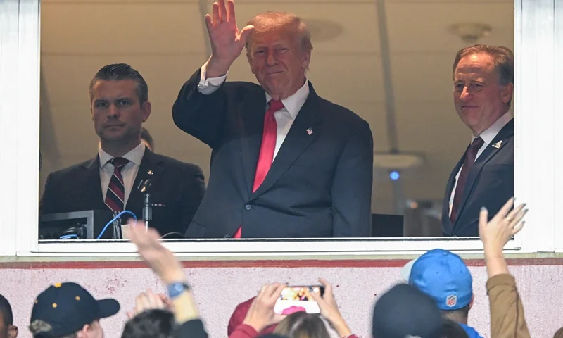 LANDOVER, MARYLAND - NOVEMBER 9: Secretary of War Pete Hegseth (L) and Commanders team owner Josh Harris (R) watch U.S. President Donald Trump greet fans as he attends the NFL football game between the Detroit Lions and Washington Commanders at Northwest Stadium on November 9, 2025 in Landover, Maryland. Trump attended the game to honor military veterans during halftime of the game. (Photo by John McDonnell/Getty Images)