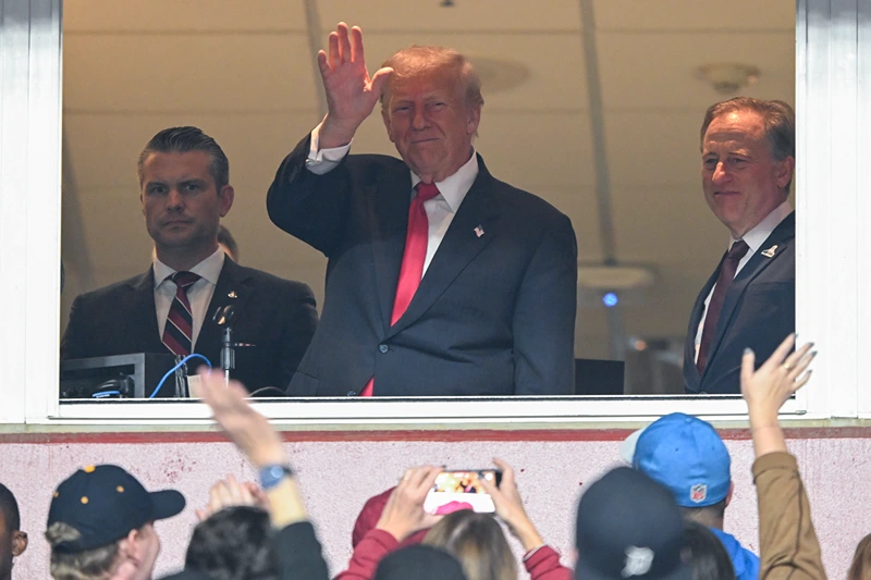 LANDOVER, MARYLAND - NOVEMBER 9: Secretary of War Pete Hegseth (L) and Commanders team owner Josh Harris (R) watch U.S. President Donald Trump greet fans as he attends the NFL football game between the Detroit Lions and Washington Commanders at Northwest Stadium on November 9, 2025 in Landover, Maryland. Trump attended the game to honor military veterans during halftime of the game. (Photo by John McDonnell/Getty Images)