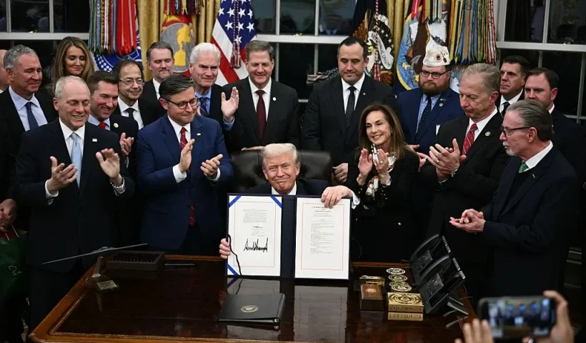 US President Donald Trump (C) shows the signed bill package to re-open the federal government in the Oval Office of the White House in Washington, DC, on November 12, 2025. Congress on Wednesday ended the longest government shutdown in US history, 43 days that paralyzed Washington and left hundreds of thousands of workers unpaid while Republicans and Democrats played a high-stakes blame game. The Republican-led House of Representatives voted largely along party lines to approve a Senate-passed package that will reopen federal departments and agencies, as many Democrats fume over what they see as a capitulation by party leaders. (Photo by Brendan SMIALOWSKI / AFP) (Photo by BRENDAN SMIALOWSKI/AFP via Getty Images)