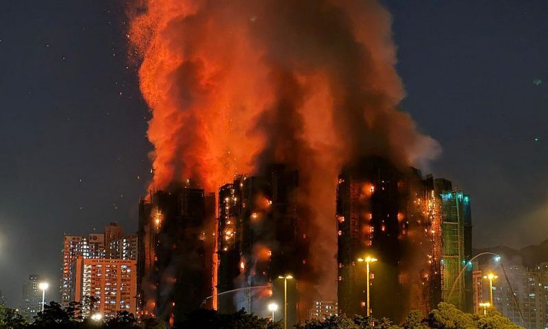 TOPSHOT - Thick smoke and flames rise as a major fire engulfs several apartment blocks at the Wang Fuk Court residential estate in Hong Kong's Tai Po district on November 26, 2025. At least four people were killed when a fire engulfed several high-rise blocks in a Hong Kong residential estate on November 26, the government said, with media reporting that some residents were trapped inside. (Photo by Yan ZHAO / AFP via Getty Images)