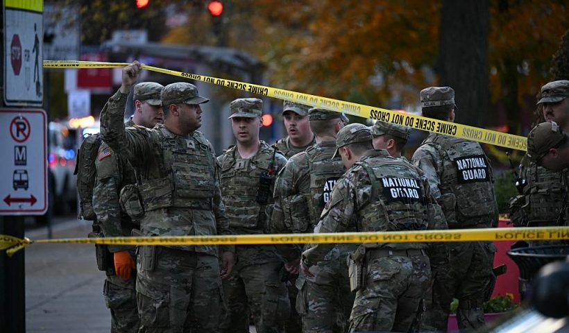 National Guard soldiers stand behind the crime scene tape at a corner in downtown Washington, DC, on November 26, 2025. Two National Guard soldiers were shot a few blocks from the White House, according to law enforcement. (Photo by Drew ANGERER / AFP via Getty Images)