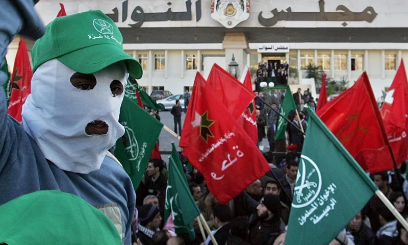 Jordanian demonstrators waving green Muslim Brotherhood flags and other banners shout anti-Israel slogans during a mass rally held outside the parliament building (background) in Amman against Israel's attacks on the Gaza Strip on January 4, 2009. Jordan's King Abdullah II demanded today that the UN Security Council issue a resolution to end Israel's "aggression" on the Gaza Strip, the royal palace said. Jordan, which signed a peace treaty with Israel in 1994, "is extremely angry and will take all necessary steps to stop the aggression," the king told a meeting of the country's council on national policies. AFP PHOTO/KHALIL MAZRAAWI (Photo credit should read KHALIL MAZRAAWI/AFP via Getty Images)