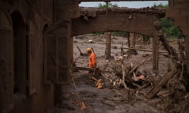 A rescue worker walks between destroyed houses after a dam burst in the town of Bento Rodrigues, Minas Gerais state, Brazil, Nov. 8, 2015. (AP Photo/Felipe Dana, File)