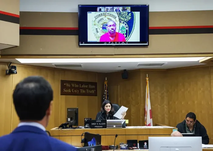 Former NFL star wide receiver Antonio Brown, on monitor above, appears for his bond hearing via video after his attorney Mark Eiglarsh, left, filed a written plea of “not guilty” for an attempted murder charge as Judge Mindy S. Glazer presides, Wednesday, Nov. 12, 2025, in Miami. (Carl Juste/Miami Herald via AP, Pool)