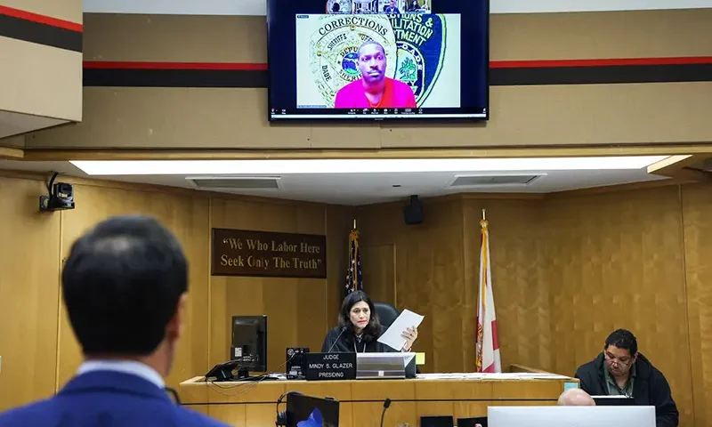 Former NFL star wide receiver Antonio Brown, on monitor above, appears for his bond hearing via video after his attorney Mark Eiglarsh, left, filed a written plea of “not guilty” for an attempted murder charge as Judge Mindy S. Glazer presides, Wednesday, Nov. 12, 2025, in Miami. (Carl Juste/Miami Herald via AP, Pool)