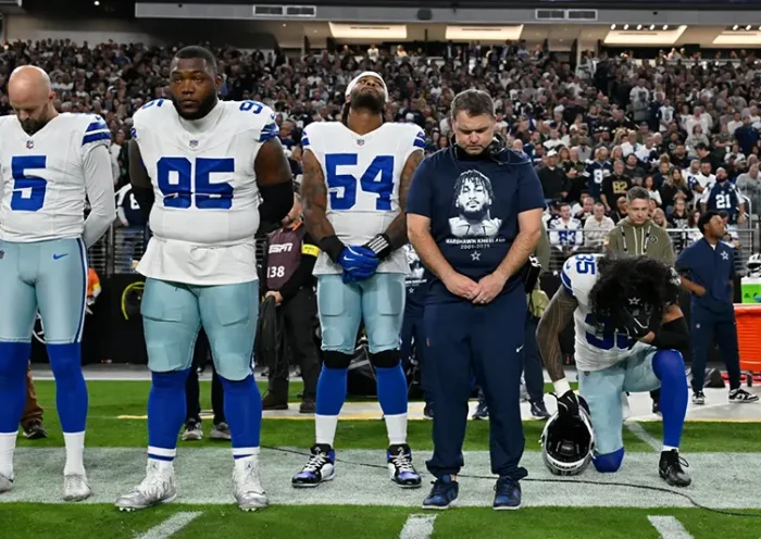 Dallas Cowboys players Bryan Anger (5), Kenny Clark (95), Sam Williams (54), Marist Liufau (35) and Cowboys linebackers coach Dave Borgonzi pause during a moment of silence for teammate Marshawn Kneeland prior to an NFL football game against the Las Vegas Raiders Monday, Nov. 17, 2025, in Las Vegas, in memory of Kneeland who passed away earlier this month. (AP Photo/David Becker)