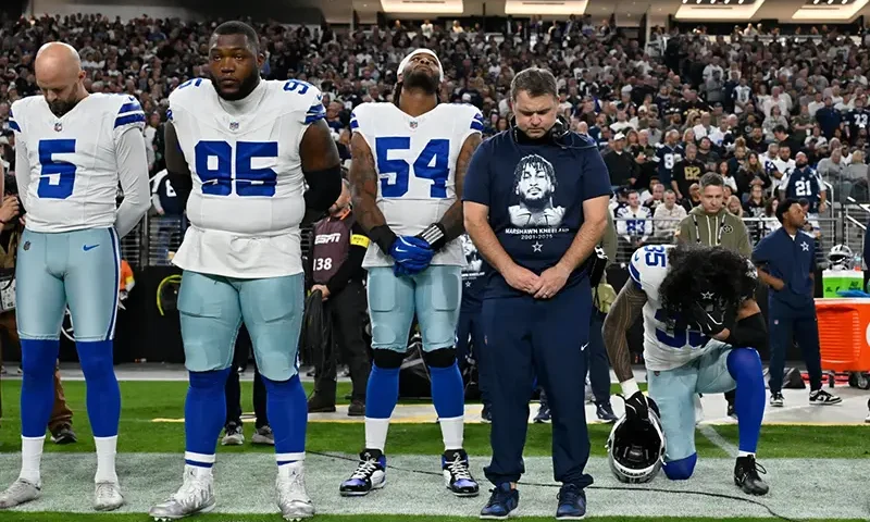 Dallas Cowboys players Bryan Anger (5), Kenny Clark (95), Sam Williams (54), Marist Liufau (35) and Cowboys linebackers coach Dave Borgonzi pause during a moment of silence for teammate Marshawn Kneeland prior to an NFL football game against the Las Vegas Raiders Monday, Nov. 17, 2025, in Las Vegas, in memory of Kneeland who passed away earlier this month. (AP Photo/David Becker)
