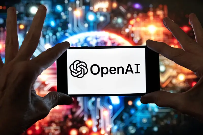 The OpenAI logo is seen displayed on a cell phone in front of an image on a computer screen generated by ChatGPT’s Dall-E text-to-image model, Friday, Dec. 8, 2023, in Boston. (AP Photo/Michael Dwyer, file)