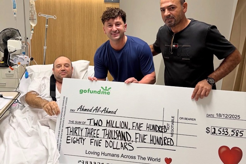 A picture shared to X shows Zachery Dereniowski (M) handing Ahmed al Ahmed (R) a check of $2,544,585 AUS, about $1.6 million USD, while he recovers in a hospital bed. (Photo: 6ixbuzztv via X)