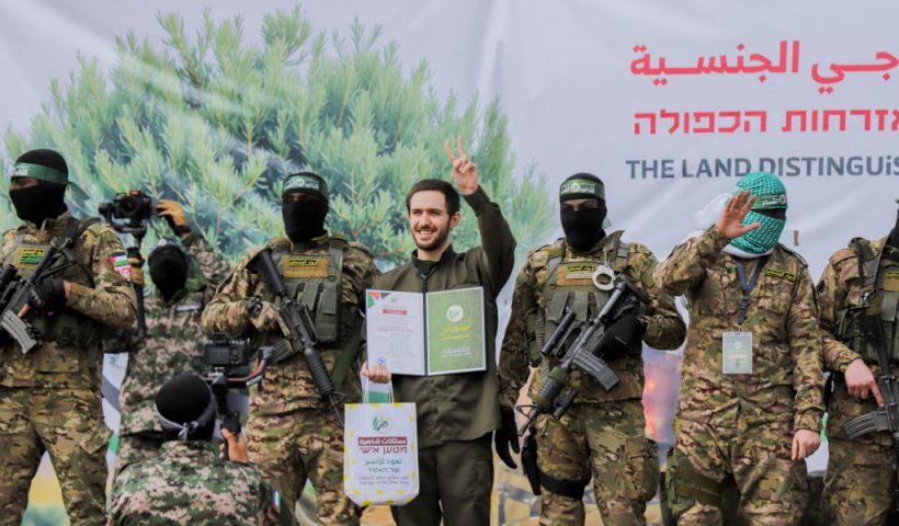 Israeli hostage Omer Shem Tov, flanked by Palestinian Hamas fighters, smiles after being released along with two others as part of the seventh hostage-prisoner exchange ,in Nuseirat in the central Gaza Strip, on February 22, 2025. Three more Israeli hostages were freed by Hamas militants at a ceremony in central Gaza on February 22 after two others were released in the southern part of the Palestinian territory. (Photo by Saeed Jaras / Middle East Images / Middle East Images via AFP) (Photo by SAEED JARAS/Middle East Images/AFP via Getty Images)