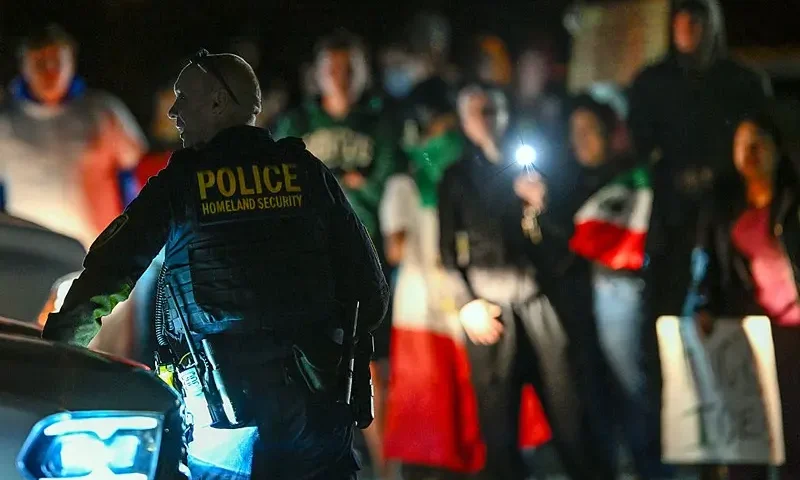 A Department of Homeland Security agent stands guard as protesters demonstrate against recent raids conducted by the US Immigration and Customs Enforcement (ICE) outside the DHS office in Charlotte, North Carolina, on November 16, 2025. Federal immigration officers began immigration enforcement operations in Charlotte on November 15, they confirmed in a statement. "We are surging DHS law enforcement to Charlotte to ensure Americans are safe and public safety threats are removed," Assistant Homeland Security Secretary Tricia McLaughlin said. US President Donald Trump has made deporting undocumented immigrants a key priority for his second term, after successfully campaigning against an alleged "invasion" by criminals. (Photo by Peter Zay / AFP) (Photo by PETER ZAY/AFP via Getty Images)