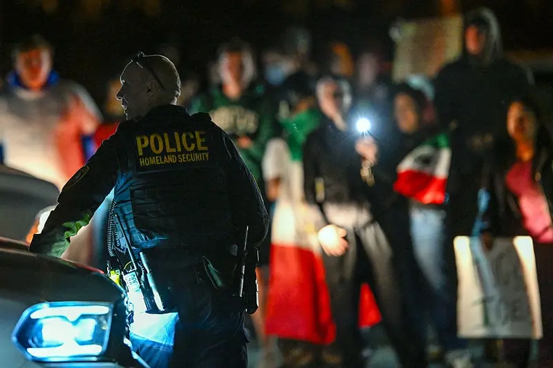 A Department of Homeland Security agent stands guard as protesters demonstrate against recent raids conducted by the US Immigration and Customs Enforcement (ICE) outside the DHS office in Charlotte, North Carolina, on November 16, 2025. Federal immigration officers began immigration enforcement operations in Charlotte on November 15, they confirmed in a statement. "We are surging DHS law enforcement to Charlotte to ensure Americans are safe and public safety threats are removed," Assistant Homeland Security Secretary Tricia McLaughlin said. US President Donald Trump has made deporting undocumented immigrants a key priority for his second term, after successfully campaigning against an alleged "invasion" by criminals. (Photo by Peter Zay / AFP) (Photo by PETER ZAY/AFP via Getty Images)