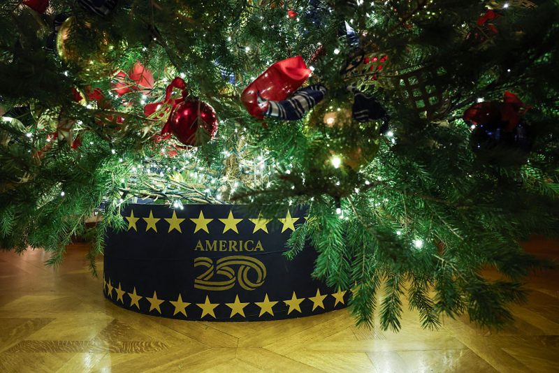 WASHINGTON, DC - DECEMBER 01: The "America 250" logo is seen on a Christmas tree skirt in the East Room during an advance tour of the 2025 White House Christmas decorations on December 01, 2025 in Washington, DC. The theme for this year's White House Christmas decorations is "Home Is Where The Heart Is." (Photo by Anna Moneymaker/Getty Images)
