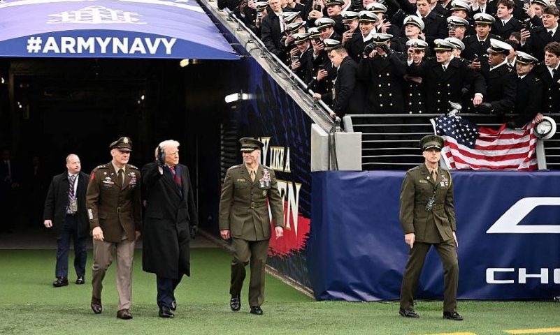 US President Donald Trump waves as he arrives on the field before the college football game between the US Army and Navy at the M&T Bank Stadium in Baltimore, Maryland, on December 13, 2025. (Photo by Alex WROBLEWSKI / AFP via Getty Images)