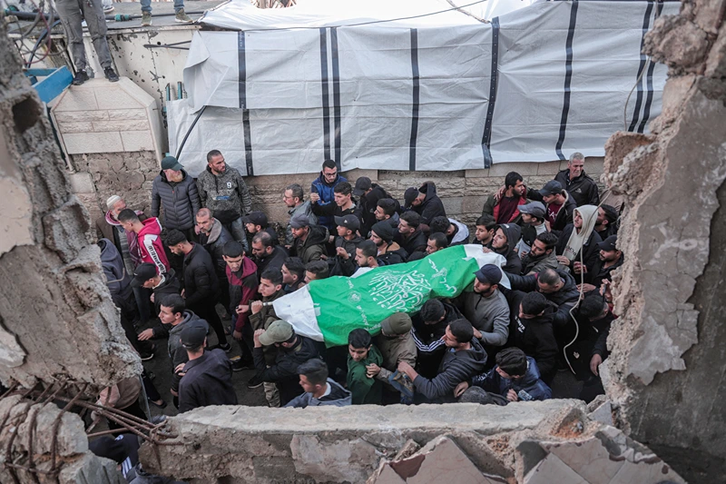 Mourners carry the body of Raid Saad, a commander of the Al-Qassam Brigades, during his funeral in the Al-Shati refugee camp in Gaza City, Gaza on December 14, 2025. Saad was killed in an Israeli airstrike that targeted a car west of Gaza City, according to Hamas. The strike occurred amid a ceasefire between Israel and Hamas. (Photo by Abood Abusalama / Middle East Images / AFP via Getty Images)