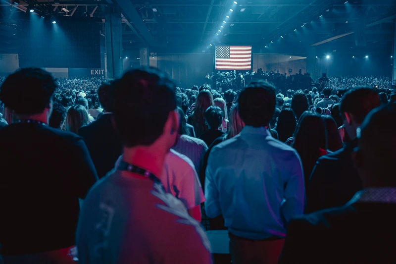 Attendees face the US flag during the national anthem at Turning Point's annual AmericaFest conference, in remembrance of late right-wing political activist Charlie Kirk, in Phoenix, Arizona on December 18, 2025. (Photo by Olivier Touron / AFP via Getty Images)