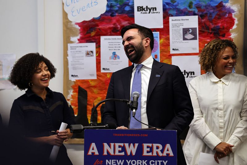 NEW YORK, NEW YORK - DECEMBER 17: Mayor-elect Zohran Mamdani speaks to members of the media at a Brooklyn library to make a transition announcement for his administration on December 17, 2025 in New York City. Jahmila Edwards (right) will be the head of the Mayor's Office of Intergovernmental Relations and Cat Da Costa (left) will become the head of the Mayor's Office of Appointments. Upon taking office, the incoming administration will seek to address a $380 million budget deficit. (Photo by Spencer Platt/Getty Images)