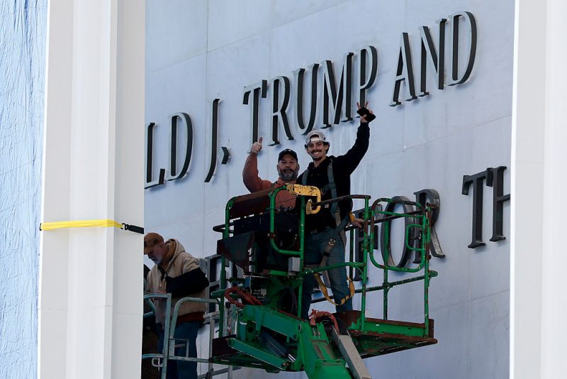 WASHINGTON, DC - DECEMBER 19: Workers pose for a photo after adjusting the name of the “John F. Kennedy Memorial Center for the Performing Arts" on December 19, 2025 in Washington, DC. The Kennedy Center Board of Trustees voted in what they say was a unanimous decision to rename the facility “The Donald J. Trump and The John F. Kennedy Memorial Center for the Performing Arts”. (Photo by Heather Diehl/Getty Images)