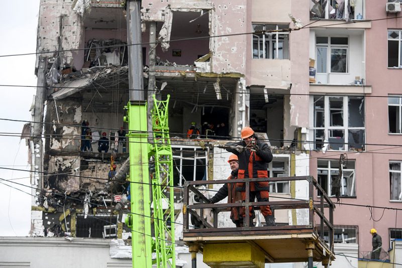 Workers repare cables in front of a damaged residential building following Russian drones and missiles attack in Kyiv, on December 27, 2025, amid the Russian invasion in Ukraine. Russia pummelled Ukraine's capital with drones and missiles on December 27, killing a woman and cutting power to hundreds of thousands, ahead of the latest talks between the presidents of Ukraine and the US. (Photo by VLADYSLAV MUSIENKO / AFP via Getty Images)