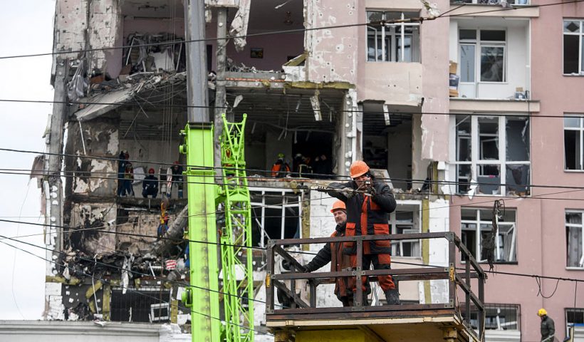 Workers repare cables in front of a damaged residential building following Russian drones and missiles attack in Kyiv, on December 27, 2025, amid the Russian invasion in Ukraine. Russia pummelled Ukraine's capital with drones and missiles on December 27, killing a woman and cutting power to hundreds of thousands, ahead of the latest talks between the presidents of Ukraine and the US. (Photo by VLADYSLAV MUSIENKO / AFP via Getty Images)