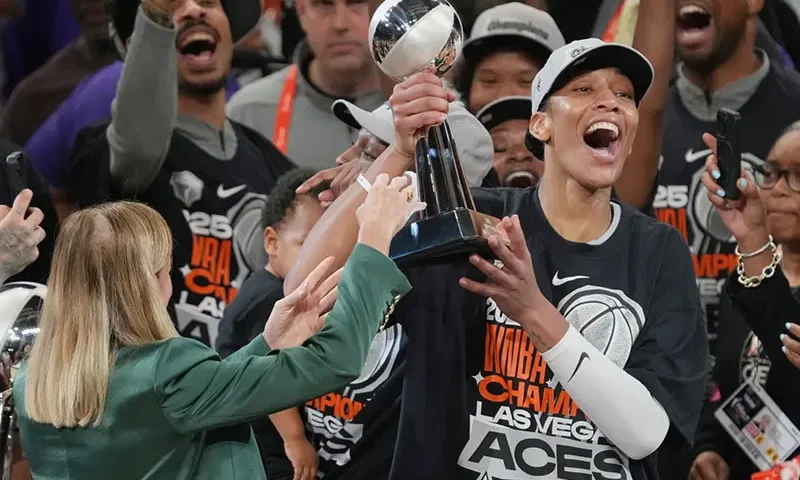 Las Vegas Aces center A’ja Wilson, center right, holds up her MVP trophy after Game 4 of the WNBA basketball finals against the Phoenix Mercury, Friday, Oct. 10, 2025, in Phoenix. (AP Photo/Rick Scuteri, File)