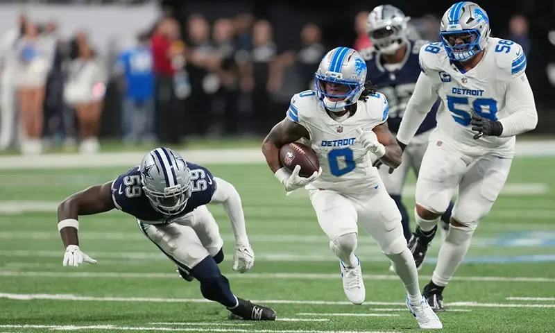 Detroit Lions running back Jahmyr Gibbs (0) runs the ball as Dallas Cowboys linebacker Jr. Kenneth Murray (59) tries to stop him during the first half of an NFL football game Thursday, Dec. 4, 2025, in Detroit.
