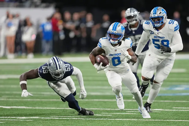 Detroit Lions running back Jahmyr Gibbs (0) runs the ball as Dallas Cowboys linebacker Jr. Kenneth Murray (59) tries to stop him during the first half of an NFL football game Thursday, Dec. 4, 2025, in Detroit.
