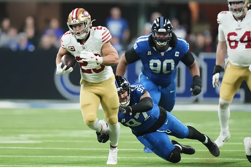 San Francisco 49ers running back Christian McCaffrey (23) runs past Indianapolis Colts defensive end Laiatu Latu (97) and defensive tackle Grover Stewart (90) during the first half of an NFL football game, Monday, Dec. 22, 2025, in Indianapolis. (AP Photo/AJ Mast)