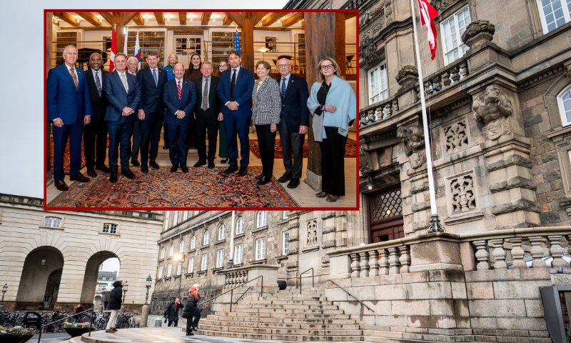 (Background) COPENHAGEN, DENMARK - JANUARY 16: Christiansborg Palace on January 16, 2026 in Copenhagen, Denmark. US Senator Chris Coons (D-DE) is leading the congressional delegation on a two-day visit to Copenhagen, where the American representatives plan to demonstrate strong bipartisan and bicameral support in Congress for our Danish NATO ally, as they discuss cooperation between Denmark, Greenland and the US. The visit follows President Donald Trump's repeated threats to annex Greenland, an autonomous territory within the Kingdom of Denmark. (Photo by Martin Sylvest Andersen/Getty Images) / (L) (L-R) US Republican Senator Thom Tillis, US Democratic Gregory Meeks, unidentified, US Democratic Representative Steny Hoyer, Danish Defense Minister Troels Lund Poulsen, US Republican Senator Lisa Murkowski, US Democratic Senator Chris Coons, US Representative Sara Jacobs, Danish Foreign Minister Lars Loekke Rasmussen, US Representative Sarah McBride, unidentified, US Senator Jeanne Shaheen, US Democratic Senator Peter Welch and US Representative Democrat Madeleine Dean pose for a family picture at the Eigtved's Warehouse in Copenhagen, Denmark, during a visit on January 16, 2026. A bipartisan US Congress delegation visited Copenhagen on January 16, 2026 to voice support for Denmark and Greenland, insisting that US President Donald Trump's designs on the Arctic island did not have the backing of the American people. The two-day visit comes alongside a European show of support in the form of a military reconnaissance mission to Greenland, a Danish autonomous territory. (Photo by Ida Marie Odgaard / Ritzau Scanpix / AFP via Getty Images) / Denmark OUT