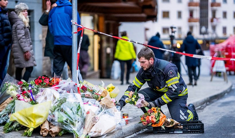 A firefighter displays flowers at a makeshift memorial near the site of a fire that ripped through a bar during New Year's Eve celebrations in the Alpine ski resort town of Crans-Montana killing around 40 people and injuring more than 100 others, in Crans-Montana on January 2, 2026. Investigators raced on January 2, 2026 to identify the victims of a fire that ripped through a bar in the Swiss Alps town of Crans-Montana, turning a New Year's celebration into one of the country's worst tragedies. Frederic Gisler, police commander in the Wallis canton in southwestern Switzerland, told reporters that authorities had counted "around 40 people who have died and around 115 injured, most of them seriously". (Photo by MAXIME SCHMID / AFP via Getty Images)