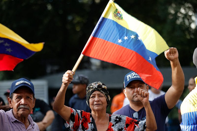 Supporters of Venezuela's President Nicolas Maduro flutter national flags in Caracas on January 3, 2026, after US forces captured Venezuelan leader Nicolas Maduro after launching a "large scale strike" on the South American country. President Donald Trump said Saturday that US forces had captured Maduro after bombing the capital Caracas and other cities in a dramatic climax to a months-long standoff between Trump and his Venezuelan arch-foe. (Photo by Pedro MATTEY / AFP via Getty Images)